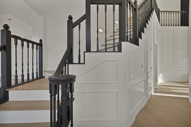 staircase featuring a decorative wall and wood finished floors