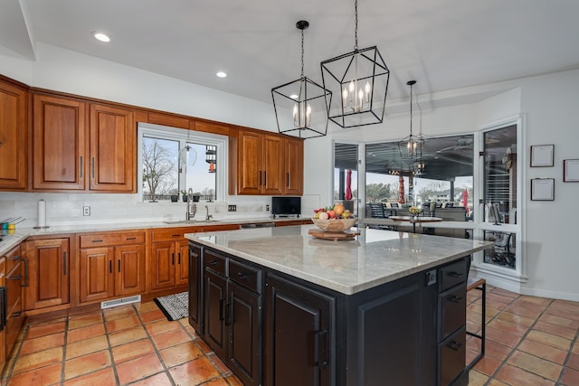 kitchen with tasteful backsplash, brown cabinetry, a center island, a sink, and recessed lighting