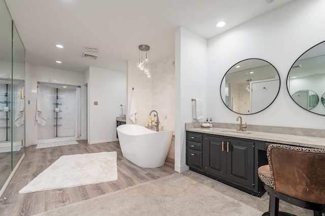 full bathroom featuring recessed lighting, a freestanding bath, a shower stall, vanity, and wood finished floors