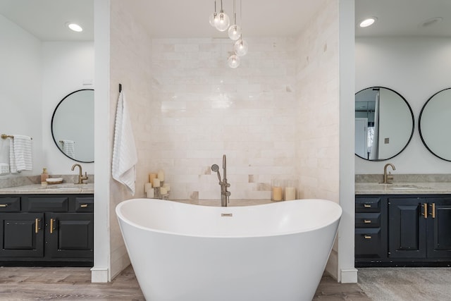 bathroom featuring a freestanding bath, two vanities, and a sink