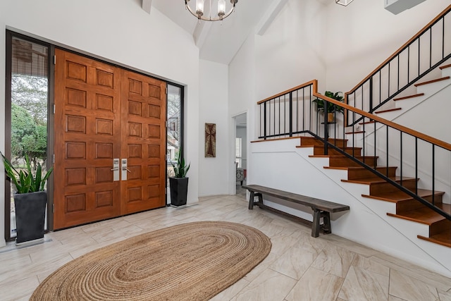 foyer entrance with a chandelier, marble finish floor, a high ceiling, and stairs