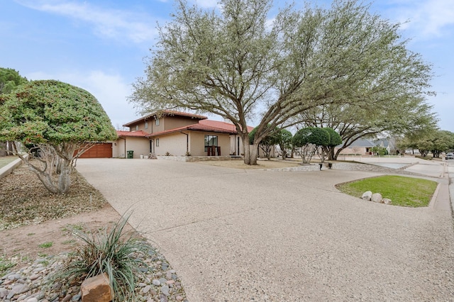 view of front of property with a tile roof, driveway, an attached garage, and stucco siding