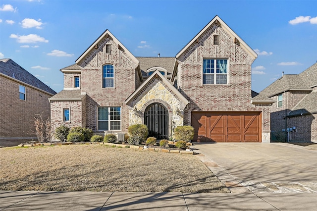 french provincial home featuring driveway, brick siding, an attached garage, and stone siding