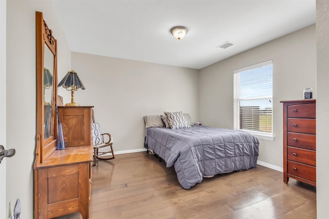 bedroom with visible vents, baseboards, and wood finished floors