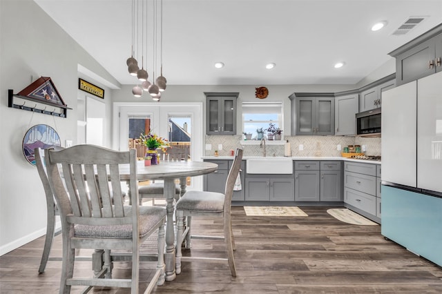 kitchen featuring tasteful backsplash, visible vents, gray cabinets, stainless steel appliances, and a sink