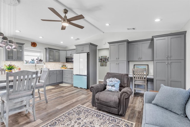 living area with lofted ceiling, ceiling fan, light wood finished floors, and visible vents