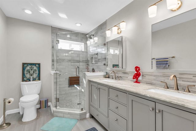 full bath featuring toilet, a shower stall, double vanity, and a sink