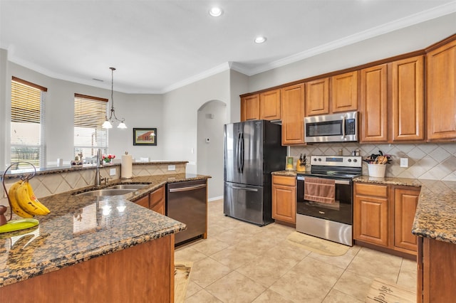 kitchen with stainless steel appliances, arched walkways, brown cabinetry, and a sink