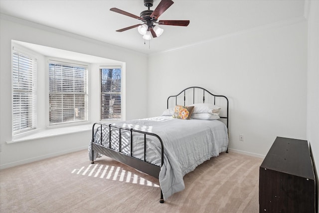 carpeted bedroom with a ceiling fan, baseboards, and crown molding