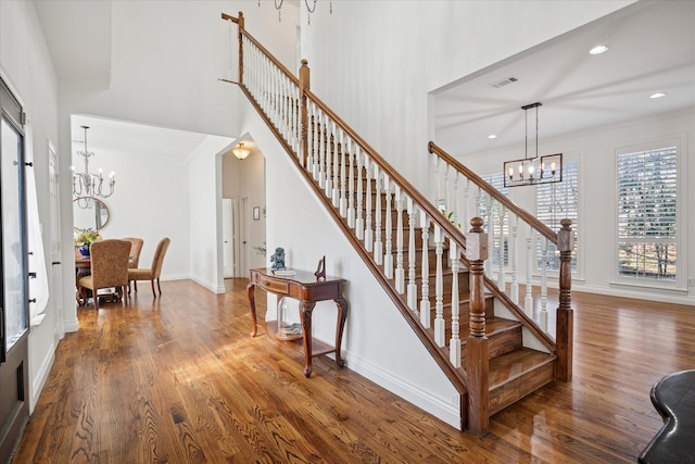 foyer with an inviting chandelier, stairway, visible vents, and wood finished floors