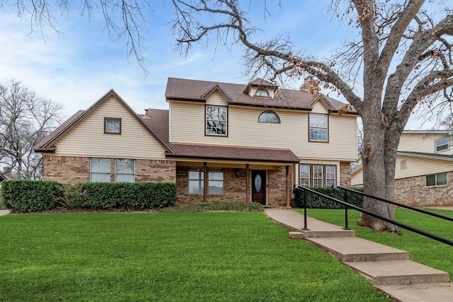 view of front of property with a front lawn, a shingled roof, and brick siding