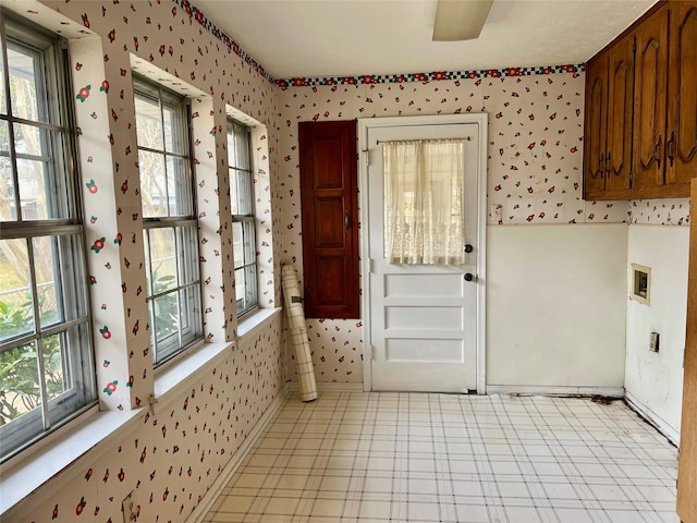 interior space featuring hookup for a washing machine, cabinet space, baseboards, and wallpapered walls