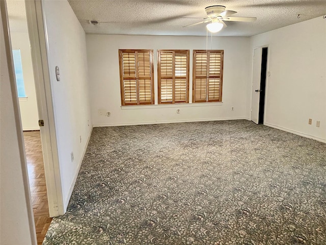 unfurnished room featuring a ceiling fan, visible vents, baseboards, and a textured ceiling