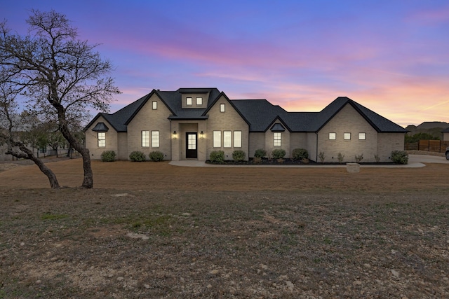 french country home featuring a front lawn and brick siding