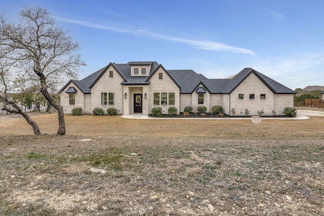 french country inspired facade featuring brick siding and a shingled roof