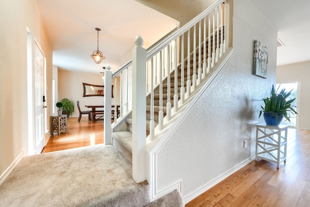 stairway featuring baseboards, wood finished floors, and a textured wall