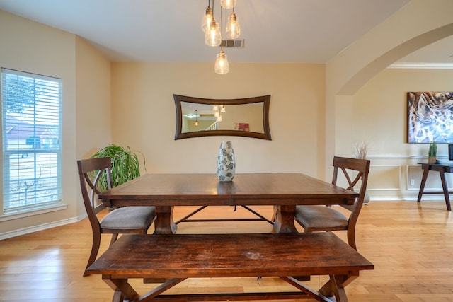 dining room with arched walkways, visible vents, and light wood finished floors