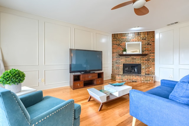 living area with visible vents, a decorative wall, and wood finished floors