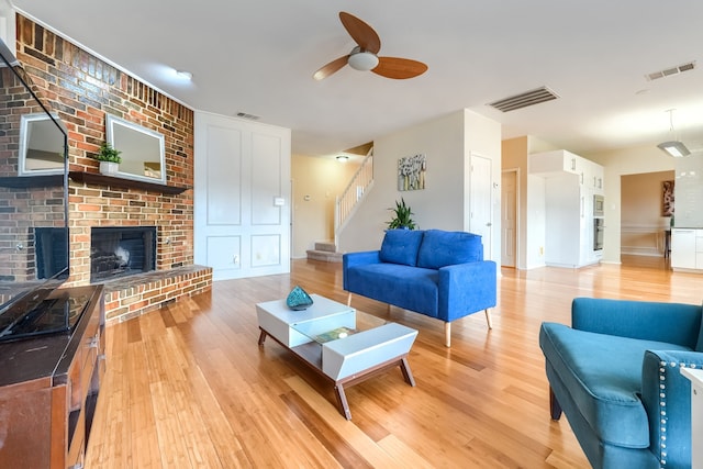 living room with light wood-style flooring, a fireplace, and visible vents