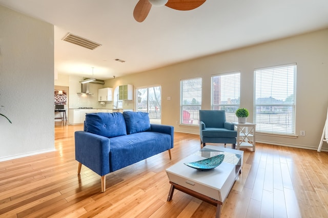 living area with light wood-style flooring, visible vents, and baseboards