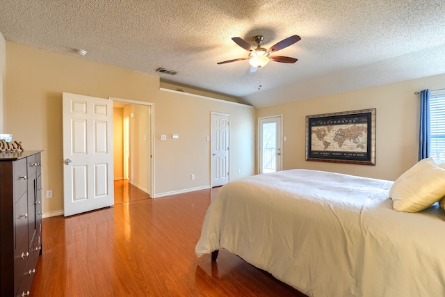 bedroom with visible vents, ceiling fan, a textured ceiling, wood finished floors, and baseboards