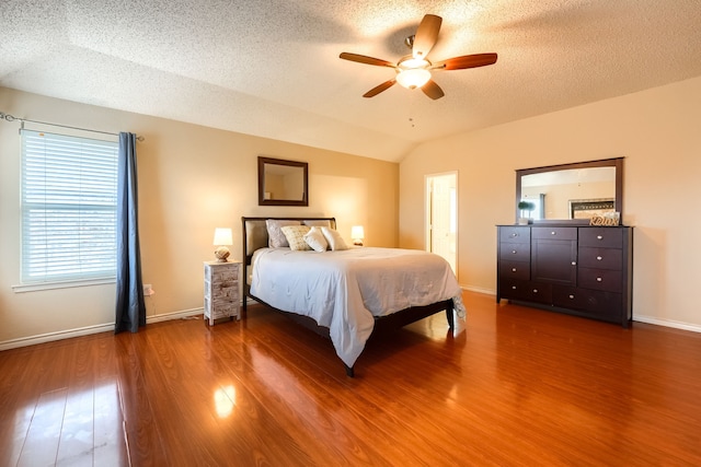 bedroom with lofted ceiling, ceiling fan, a textured ceiling, wood finished floors, and baseboards