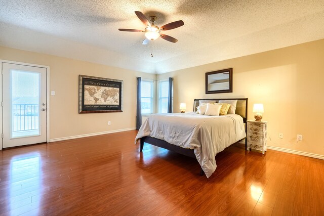 bedroom featuring a textured ceiling, access to outside, wood finished floors, and baseboards