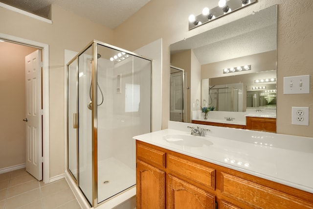 full bathroom with a textured ceiling, a stall shower, tile patterned flooring, and vanity