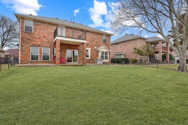 back of property featuring a balcony, a fenced backyard, a lawn, and brick siding