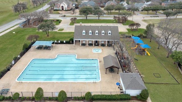 community pool featuring a lawn, a patio area, and fence