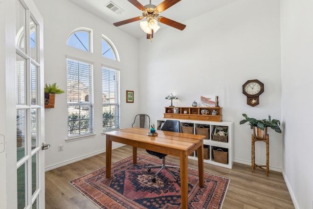 home office with light wood-style floors, baseboards, visible vents, and ceiling fan