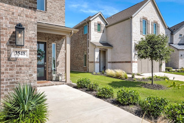 property entrance with a garage, concrete driveway, brick siding, and a lawn