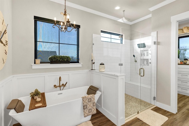 full bathroom with a wainscoted wall, a freestanding bath, ornamental molding, a shower stall, and wood finished floors