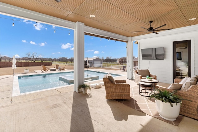 view of patio featuring a ceiling fan, a pool with connected hot tub, and a fenced backyard