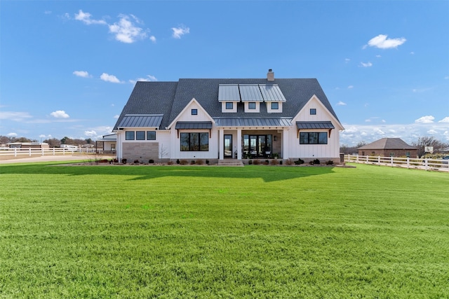 rear view of house featuring a yard, a standing seam roof, fence, and metal roof