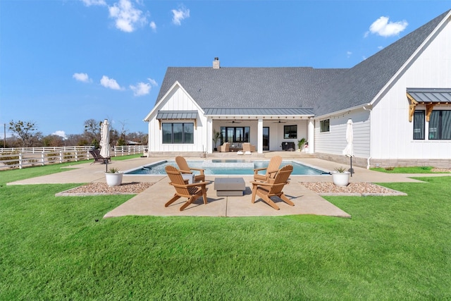 rear view of house featuring a lawn, metal roof, a standing seam roof, fence, and a patio area