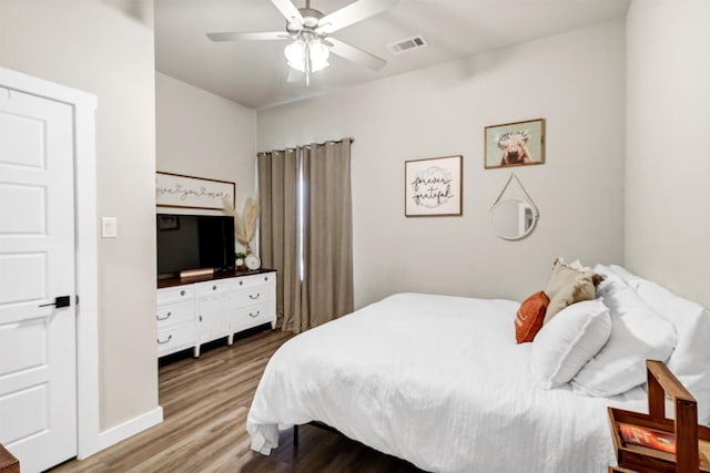 bedroom with baseboards, wood finished floors, visible vents, and a ceiling fan