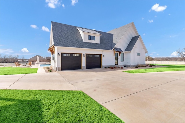 modern farmhouse with metal roof, fence, concrete driveway, roof with shingles, and a front yard