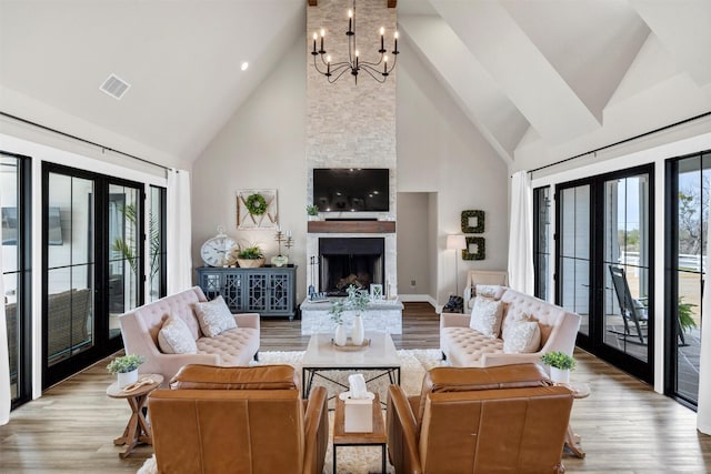 living area with a chandelier, french doors, a healthy amount of sunlight, and a fireplace