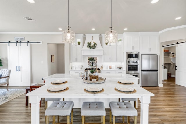 kitchen with white cabinets, a barn door, custom range hood, and stainless steel appliances