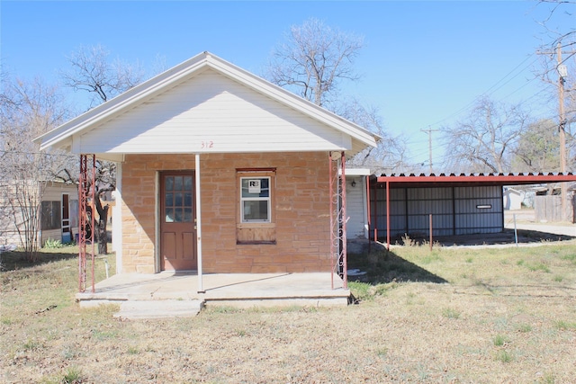 back of property featuring stone siding and a lawn