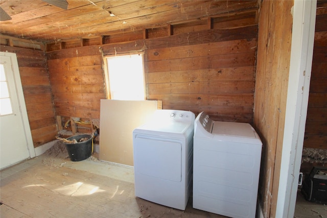 clothes washing area with wooden walls, laundry area, and washer and dryer