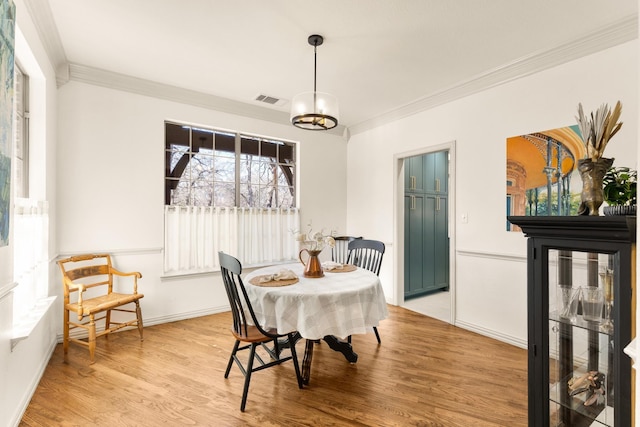 dining area featuring baseboards, ornamental molding, visible vents, and light wood-style floors