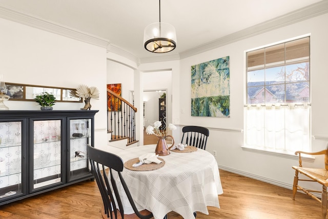 dining room with a wealth of natural light, stairway, ornamental molding, and wood finished floors