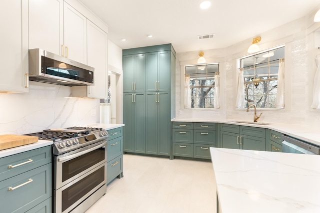 kitchen featuring a sink, visible vents, appliances with stainless steel finishes, light stone countertops, and green cabinetry