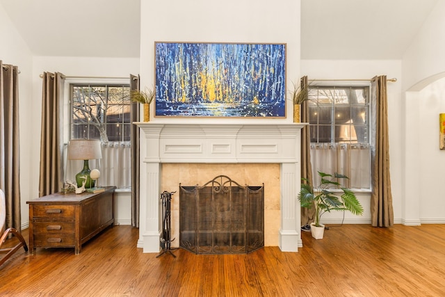 living room with vaulted ceiling, a fireplace, baseboards, and wood finished floors