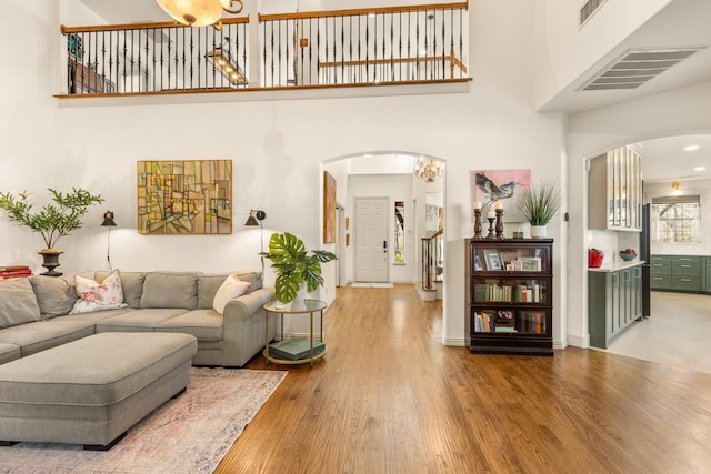 living area featuring visible vents, stairs, arched walkways, and wood finished floors