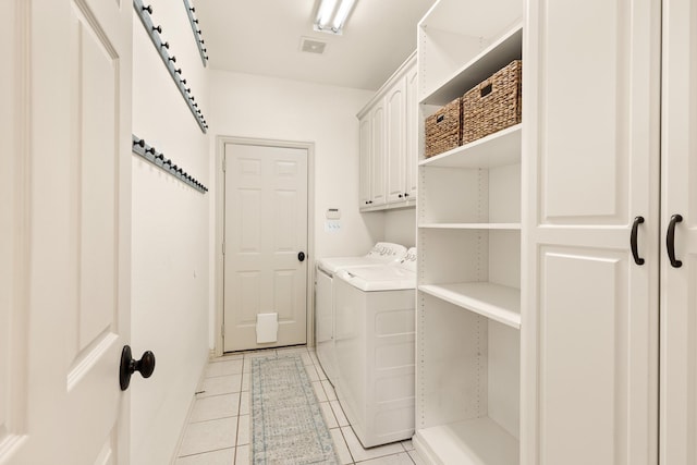 washroom featuring light tile patterned floors, visible vents, washer and clothes dryer, and cabinet space