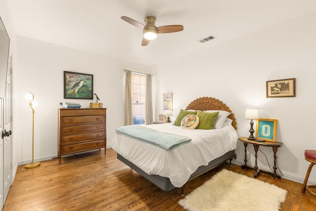 bedroom featuring baseboards, a ceiling fan, visible vents, and light wood-style floors