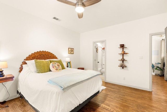 bedroom featuring ensuite bath, baseboards, visible vents, and wood finished floors